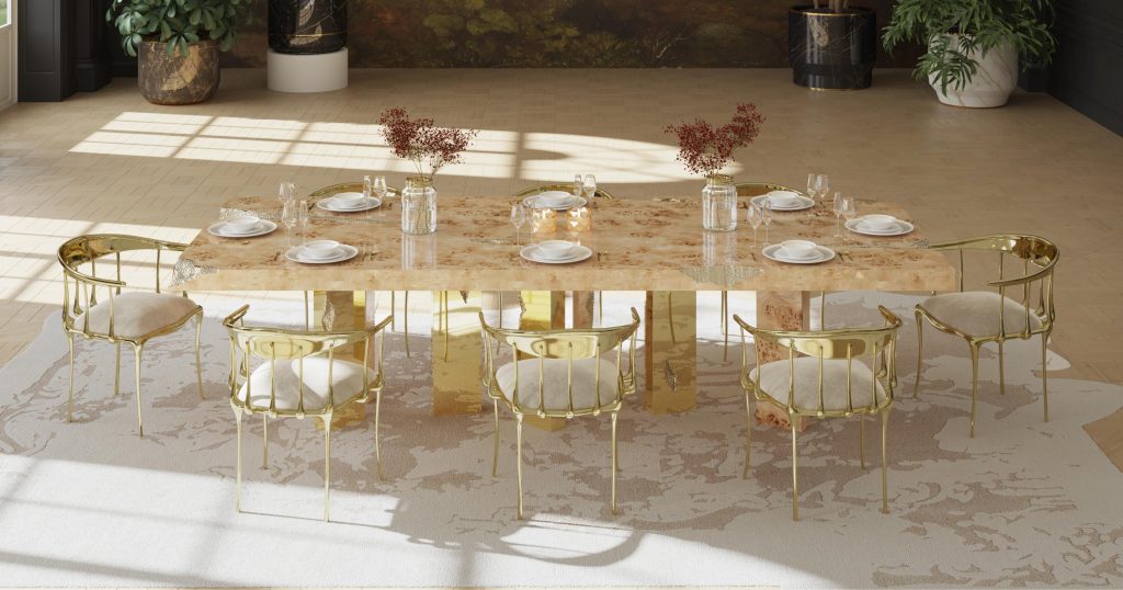 Unique Dining Tables: Luxury dining room featuring the Empire Poplar dining table with a warm, natural wood finish, set with gold-framed chairs and decorated with minimalist tableware and floral accents, on a soft, patterned rug.